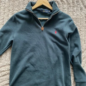 Half zip up Ralph Lauren - Säljer en snygg mörk grön från Ralph Lauren med dragkedja vid halsen . Tröjan har långa ärmar och är i mycket bra skick. Passar även M