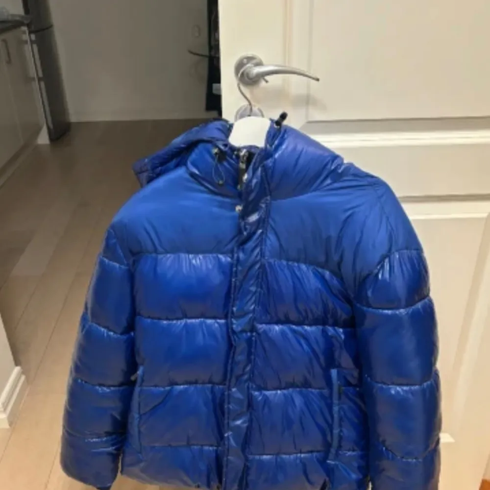 Säljer en snygg blå pufferjacka från Armani Exchange. Jackan har en glansig finish och är perfekt för kalla dagar. Den har en huva och stängs med dragkedja. Perfekt för både höst och vinter! Storlek L, fint skick på den. Passar både män och kvinnor/unisex. Finns i Örebro. Kan fraktas, köparen står för fraktkostnad.  Köpt på Boozt. . Jackor.