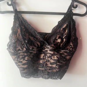 Svart spetslinne från Amisu - Säljer ett snyggt svart spetslinne från Amisu i storlek XS. Det är perfekt för festliga tillfällen med sin eleganta spetsdesign och smala axelband. Linnet är i mycket bra skick och ger en chic look till vilken outfit som helst.