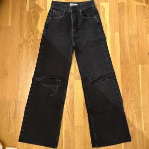 Svarta jeans med slitningar - Säljer ett par svarta jeans i mycket bra skick. De är högmidjade och har en loose passform med slitningar på knäna för en cool look. Perfekta för både vardag och fest! 🖤