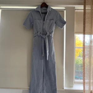 Ljusblå byxdress med knytband - Säljer en superfin ljusblå byxdress från & Other Stories med korta ärmar och knytband i midjan. Byxdressen har en dragkedja framtill och två bröstfickor. Använd endast 1 gång. Den säljes fortfarande på & Other Stories hemsida och nypriset är: 1390kr
