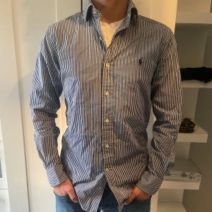 Ralph lauren skjorta  - En jättefin Ralph lauren skjorta i vit och marinblå färg. Skjortan är nästan helt oanvänd och har inga defekter, skick 10/10. Tveka inte på att höra av er om frågor, pris kan diskuteras 