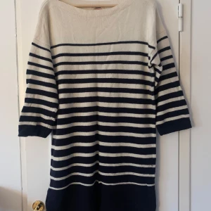 Jean Paul Gaultier stickad klänning stl M - En var snygg stickad klänning designad av Jean Paul Gaultier i samarbete med Lindex. Den är off white och marinblå. Snygg till höga stövlar. 