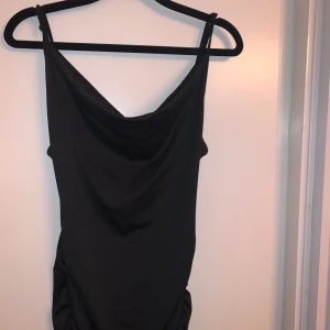 Svart långklänning - Säljer en elegant svart långklänning med smala axelband. Klänningen har en stilren design med slits nertill. Materialet är mjukt och bekvämt, knappt använd. Står inte storlek men sitter som en S