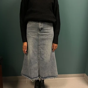 Denim kjol A linje, lite längre där bak - En denimkjol med en A-linjeform. Kjolen har en hög midja och en något längre längd. Den har en sliten look med en rå kant i nederkanten. För tajt i midjan därav säljer den så om du vet att den passar dig hör av dig. Den är jättefin i verkligheten