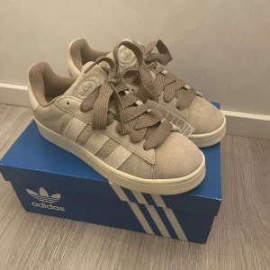 Adidas Campus 00s ”wonder beige” - Säljer ett par Adidas Campus i färgen ”wonder beige” som tyvär blev fel storlek. Dem är köpta från Merchsweden. Storleken är 41 1/3 men passar mindre. Skorna är endast testade och kommer med låda och kvitto☺️ Tveka inte på att ställa några frågor🫶🏼