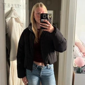 Svart pufferjacka från Vero Moda - Säljer en svart pufferjacka från Vero Moda. Den är perfekt för kyliga dagar med sin vadderade design och dragkedja framtill. Jackan har en justerbar dragsko i nederkanten för bättre passform. Den är i bra skick och redo för en ny ägare!