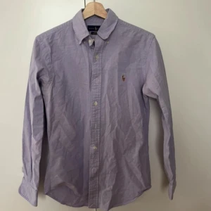 Ljuslila skjorta från Ralph Lauren - Säljer en stilren ljuslila skjorta från Ralph Lauren. Skjortan har långa ärmar och klassiska knappar framtill. Perfekt för både vardag och fest! 💜