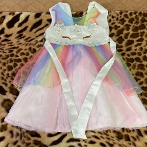 Regnbågsfärgad klänning med blommor - Söt klänning i regnbågsfärger med blommiga detaljer och ett band i midjan. Den har en ärmlös design och en fluffig kjol i flera lager. Perfekt för festliga tillfällen eller sommarkalas!