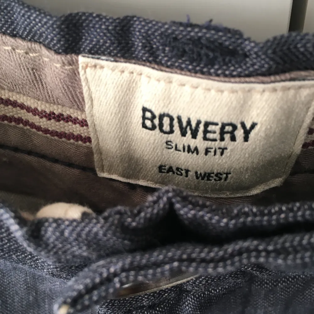 Säljer ett par blågrå Bowery byxor i slim fit. Storlek: W31 L32. De har en stilren design med knappar och dragkedja. De har lite struktur i mönstret, zooma in för att se. . Jeans & Byxor.