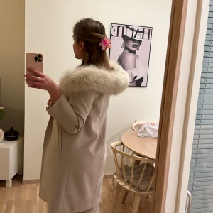 Ullkappa med äkta päls - Beige/vit kappa från märket Hollies. Inte använt så mycket. Storlek 36. Hittar inte bältet till kappan så har beställt ett nytt liknande bälte. Köptes för cirka 6000 kr