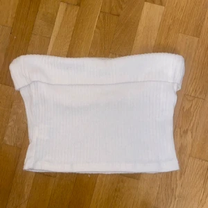 Vit ribbad tubtopp - Säljer en vit ribbad tubtopp i mycket bra skick. Den har en tight passform som framhäver figuren. Säljer då jag köpt fel storlek!