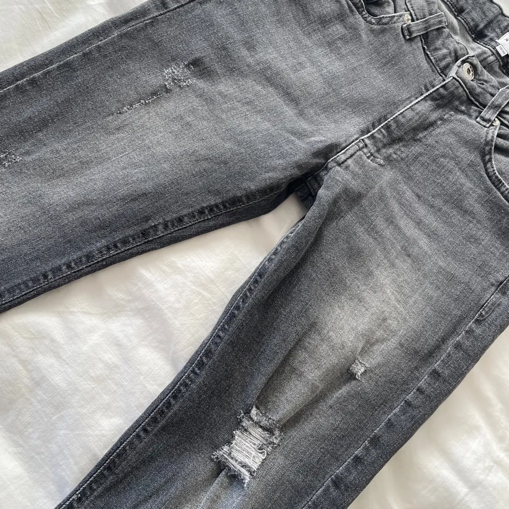 Säljer ett par grå jeans från RVLT i storlek 158/164. De har en cool slitningseffekt på framsidan och en bekväm passform. Perfekta för en avslappnad stil med en touch av edge. Passar både till vardags och festligare tillfällen.. Jeans & Byxor.