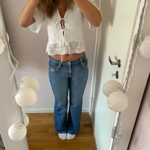 Blå jeans med broderade bakfickor - Säljer ett par snygga blå jeans i mycket bra skick. De har en klassisk bootcut-stil och är lågmidjade. Bakfickorna är broderade med ett fint mönster. 💕