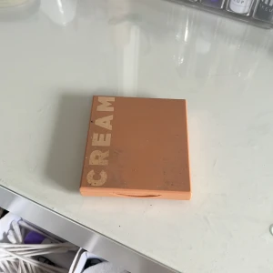 Krämbronzer i brun nyans - Säljer en krämbronzer i en snygg brun nyans. Perfekt för att ge ansiktet en solkysst look. Kommer i en praktisk fyrkantig förpackning med spegel. Använd men fortfarande mycket kvar.