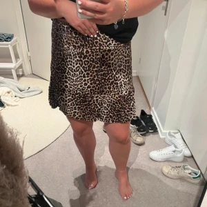 Leopardmönstrad kjol - Säljer en superfin leopardmönstrad kjol som är perfekt för både vardag och fest. Kjolen är kort och har en volangdetalj längst ner som ger den en extra touch. Den är gjord av ett mjukt och bekvämt material som känns skönt mot huden. Passar perfekt till en enkel topp och sneakers eller klackar för en mer uppklädd look. 🐆✨