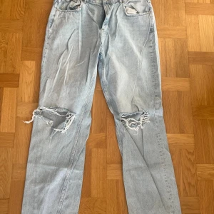 Raka blå jeans - Raka blå jeans från Gina tricot. Dessa har hål på knäna och är i storlek 46.
