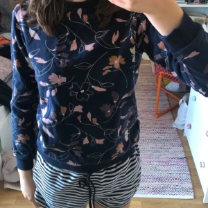 Blommig tröja från Polarn O. Pyret - Säljer en superfin blommig tröja från Polarn O. Pyret i storlek 146/152 (10-12 år). Tröjan är mörkblå med ett vackert blommönster i rosa och beige. Den är långärmad och gjord av mjukt bomullsmaterial. Perfekt för höst och vår! 🌸