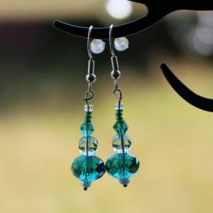 Blå och gröna pärlörhängen - Säljer ett par superfina örhängen med blå och gröna pärlor. De har en elegant design med flera pärlor i olika storlekar och former som hänger i en rad. Perfekta för att ge en färgklick till din outfit!