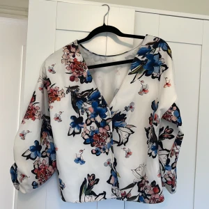 Blus - Vit blus med blommigt mönster i blått 