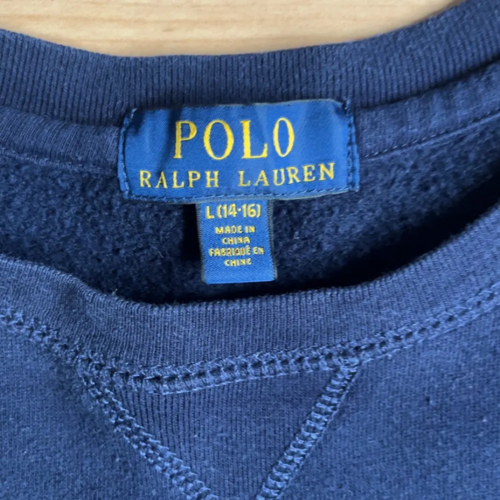 Säljer en snygg och bekväm mörkblå tröja från Polo Ralph Lauren. Tröjan är i storlek L och har en klassisk design med en liten röd logga på bröstet. Den är långärmad och perfekt för höst- och vinterdagar. Materialet känns mjukt och skönt mot huden. Perfekt för både vardag och avslappnade tillfällen.. Tröjor & Koftor.