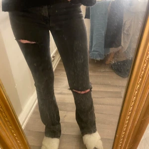 Svarta jeans med slitningar - Säljer ett par svarta/mörkgråa jeans med coola slitningar på knäna. De har en tight passform och är i en klassisk jeansstil. Perfekta för en avslappnad look med en twist! Byxorna är från lager 157 och säljer dom för kommer inte till användning 