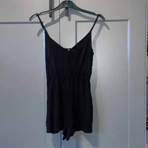 Svart Playsuit/bodysuit/shortsdress från H&M i storlek 34. Är i fint bra skick. Använd få gånger. Bysten är stängd med hjälp av en knapp. Linne och shorts ihopsatta.