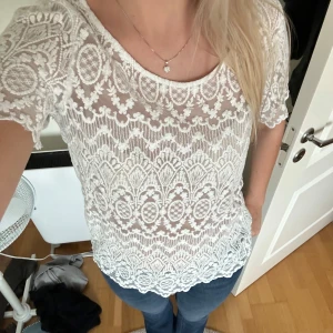 Vit spetsblus - Säljer en superfin vit spetsblus med korta ärmar. Den har ett detaljerat mönster och är perfekt för både vardag och fest. Blusen är i nyskick. Står inte på vart den är ifrån men skulle gissa Lindex eller H&M.