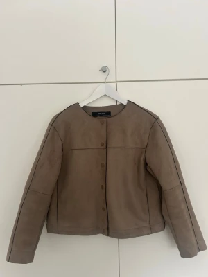 Beige cardigan jacka från Zara  - Stilren beige/brun cardigan jacka från Zara med rund halsringning och knappar framtill. Jackan har lång ärm och är tillverkad i ett mockaliknande material. Mycket fint skick och säljer då den är för liten för mig! Kan skicka fler blider vid intresse! ☺️🤎