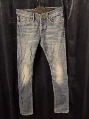 Blå jeans från AllSaints - Snygga blå jeans från AllSaints med slitna detaljer och klassisk femficksdesign. Tillverkade i mjukt bomullsmaterial med en touch av stretch för extra komfort. Skriv för frågor. (Storlek w30) 