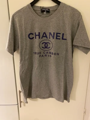 T-shirt med tryck  - Helt ny T-shirt med tryck. Står storlek L, men en M mer. Aldrig använd, men ingen lapp på.