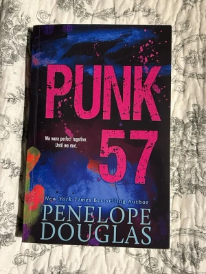 Punk 57 av Penelope Douglas - Punk 57 är en ungdomsroman med svart, blå och rosa omslag, designad med färgstänk och stora bokstäver. Boken handlar om Misha och Ryen, två tonåringar som brevväxlar och deras relation utvecklas genom missförstånd och känslor. Perfekt för dig som gillar intensiva berättelser.