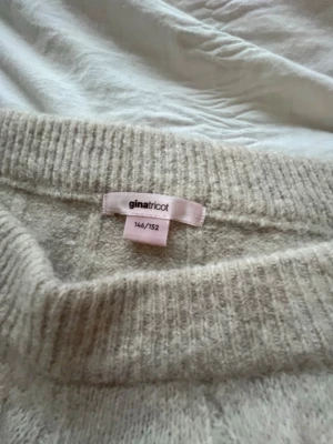 Beige kabelstickad tröja Gina Tricot - Mysig beige kabelstickad tröja från Gina Tricot med bred ribbad mudd vid ärmslut och nederkant. Tröjan har rund halsringning och ett klassiskt flätmönster på både fram- och baksida samt ärmar. Perfekt för kalla dagar och enkel att matcha.🤎