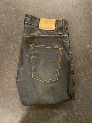 Nudie Jeans slim jim - Säljer et par mörkblåa Nudie jeans med snygg tvätt, storlek 31/32, straight fit och även lite bootcut i min syn. Mycket fint skick där de helt oanvända. Byxorna har lita glansigt material och känns lite annorlunda från jeans. Mycket Sällsynta jeans!                                                        Mått: A=39cm B=84cm C=109cm D=20cm Fråga gärna om fler bilder eller om det är något ni generellt undrar!                                                     Checka in profilen för liknande jeans!
