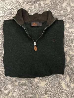 Morris half zip  - Mörkgrön stickad tröja från Morris med halv dragkedja och hög krage i kontrasterande brun färg. Tröjan har en diskret logga broderad på bröstet. Det är storleken M men den har krympt till XS men det är ingen skillnad på kvaliten skriv gärna om ni har någon fråga 😊