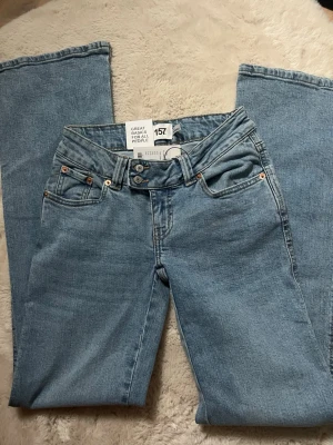 Ljusblå broderade jeans från 157 - Säljer ett par ljusblå jeans från 157 med snyggt broderi på bakfickan och klassisk femficksmodell. Jeansen har raka ben och normal passform, perfekta till en avslappnad stil. Materialet är mjukt denim i bomull.