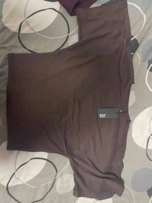 Brun t-shirt från 157 i bomull - Säljer en basic brun t-shirt från 157 i mjuk bomull. T-shirten har rund halsringning och klassisk passform, perfekt att matcha med jeans eller shorts. Enkel och stilren design utan tryck eller mönster.