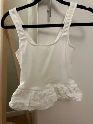 Vit linnetopp med volangkant - Supergullig topp, endast använd en gång så superfint skick. Den är tvättad och därför skrynklig där nere men de går att lösa genom att stryka