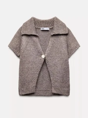 Beige stickad kofta från Zara - Kortärmad beige stickad kofta från Zara med bred krage och en dekorativ knapp framtill. Perfekt att slänga över en topp för en avslappnad men ändå stilsäker look.