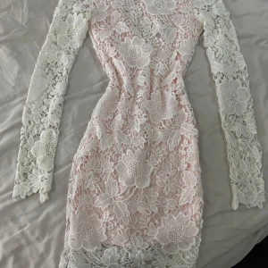 Vit spetsklänning med lång ärm - Säljer en superfin vit spetsklänning med lång ärm och v-ringning. Klänningen har ett vackert blommigt mönster och en tight passform som framhäver figuren. Perfekt för vårens och sommarens fester! 🌸
