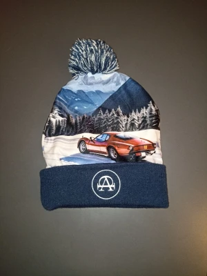 Blå mössa med bilmotiv och tofs - Snygg vintermössa med tofs och coolt motiv av en röd sportbil i vinterlandskap 🌨️🚗 Mörkblå kant med broderad logga framtill. Den är från all cap one. 🧵 Skön och varm 🧢 Stretch – passar de flesta 👌 Bra skick, inga hål eller fläckar Perfekt till vintern eller som statement-accessoar. Den är helt ny  Skickas eller möts upp – köparen står för frakt. Pris kan diskuteras vid snabb affär 