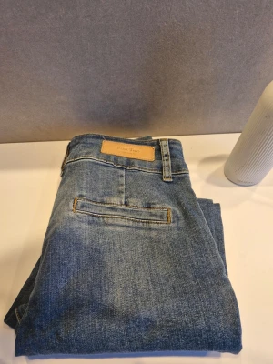 Blå jeans från Part Two, storlek 26 - Snygga blå jeans från Part Two i klassisk modell med raka ben och normal passform. Jeansen har en enkel bakficka och stängs med knapp och dragkedja. Perfekta till en avslappnad stil och tillverkade i mjukt bomullsmaterial. Helt nya bara tvättade en gång