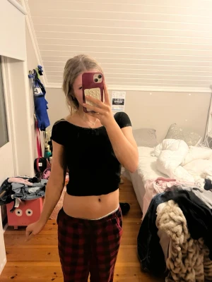 Svart croppad topp med spetskant - En svart croppad topp från Lager 157 med korta ärmar och fina spetsdetaljer längs halsringningen och ärmsluten. Toppen har en slim passform och är perfekt för en trendig och enkel look.