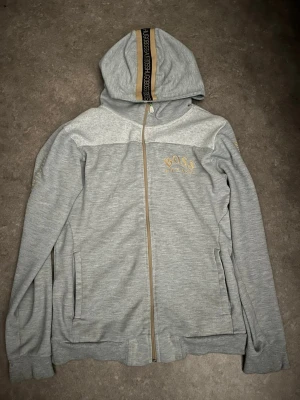 Hugo boss - En hugo boss kofta med guldig rander på armarna och bröst logan och även huve, stil ren skön att rocka!