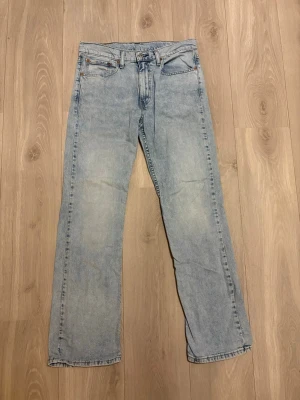 Levi's 527 ljusblå bootcut jeans - Säljer ett par ljusblå Levi's 527 jeans med klassisk femficksdesign och bootcut passform. Jeansen har en snygg tvättad look, normal midja och är tillverkade i slitstarkt bomullsjeansmaterial. Perfekta för dig som gillar en avslappnad men stilren vibe.
