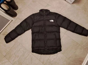Svart dunjacka från The North Face - Jag säljer nu min i stort sett oanvända (använd ca 5 gånger) svarta dunjacka från the north face. Svart jacka med logga på bröstet och bak på axeln. Jackan sitter perfekt på mig (182cm). Jackan är köpt ny för 3000sek.
