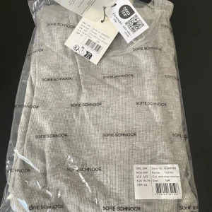 Grå ribbad långklänning Sofie Schnoor - Snygg långklänning från Sofie Schnoor i ljusgrå melange med diskret ribbad struktur. Klänningen har lång ärm, rund hals och en rak, enkel siluett. Perfekt för dig som gillar minimalistisk och clean stil. Materialet är mjukt och stretchigt för skön passform.