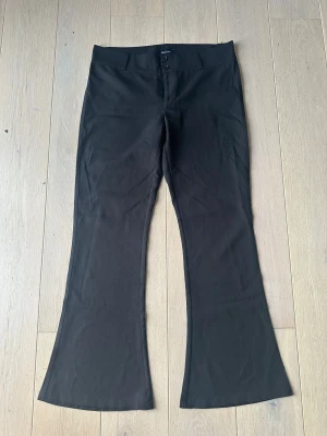Kostymbyxor från Gina tricot  - Svarta kostymbyxor med bootcut från Gina Tricot i storlek XL. Byxorna har två knappar i midjan samt två fickor där bak.  Obs: Alla plagg säljs endast fram till 28/12 