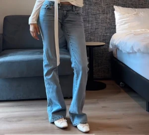 Bootcut ljusblå jeans med broderad ficka, storlek M! - Säljer ett par ljusblå bootcut jeans från Levi's med klassisk femficksdesign och snygg broderad detalj på bakfickan. Jeansen har normal passform och är tillverkade i mjukt denim. Perfekt för dig som gillar retrovibbar och vill ha ett par jeans med lite extra attityd.