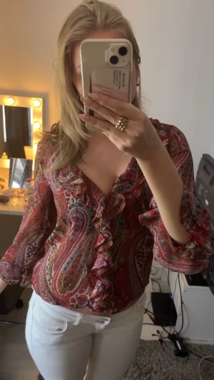 Mönstrad blus med volang  - Säljer en färgstark blus från Zara. Blusen har v-ringning med volangdetaljer längs halsen och framtill. Materialet är lätt och luftigt. Lite genomskinlig.